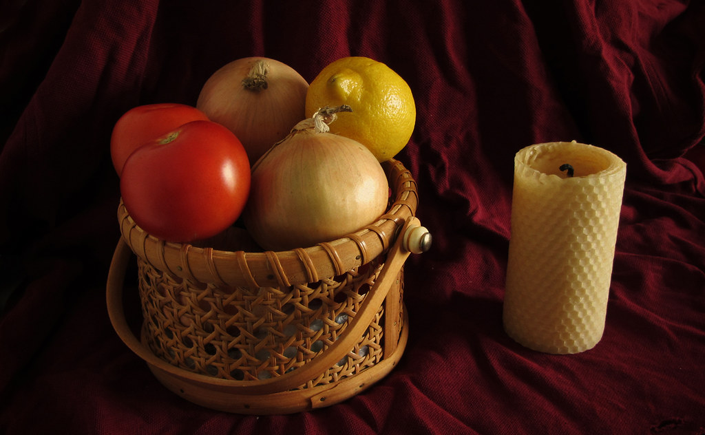 A single lit candle on a windowsill beside a folded blanket in soft morning light