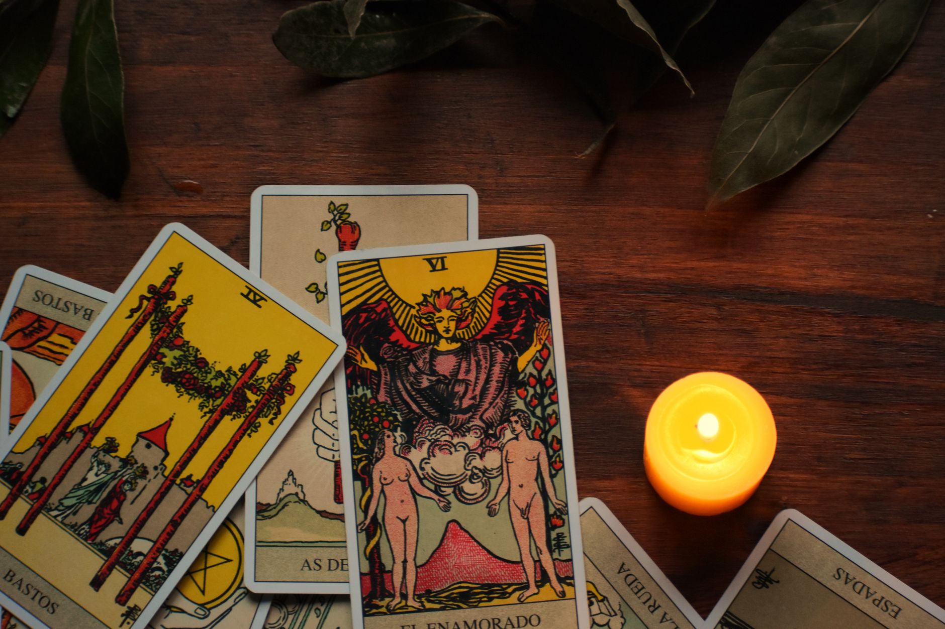 Tarot cards laid out on a table in warm candlelight during a late-summer reading